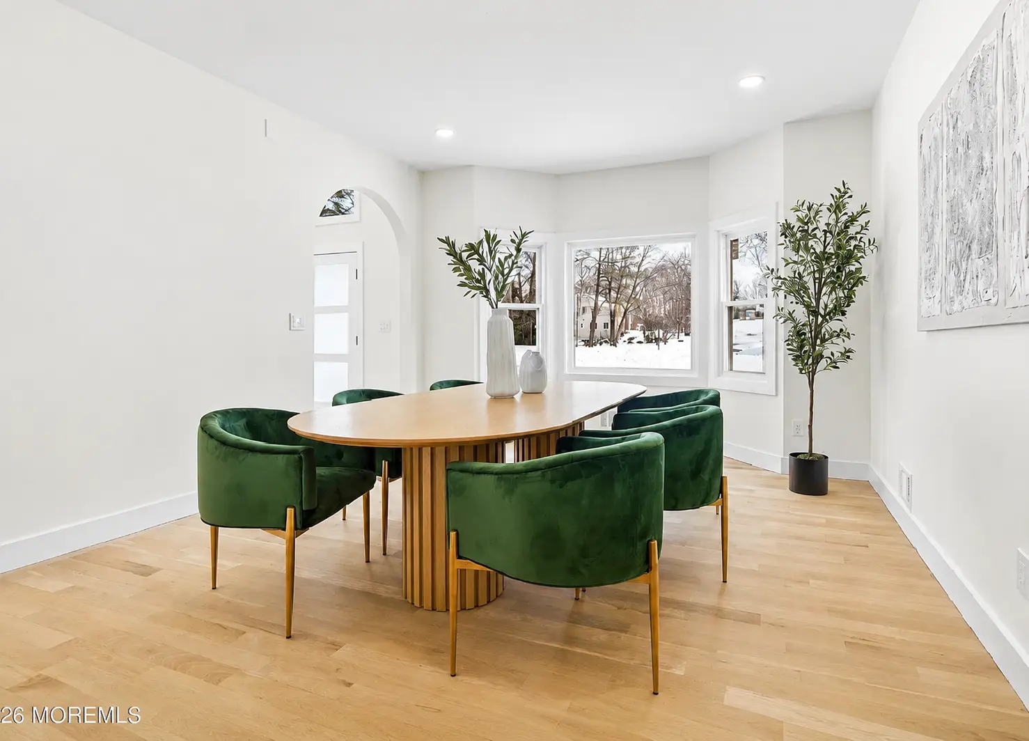 Dining room with green velvet chairs, round table, and bay window